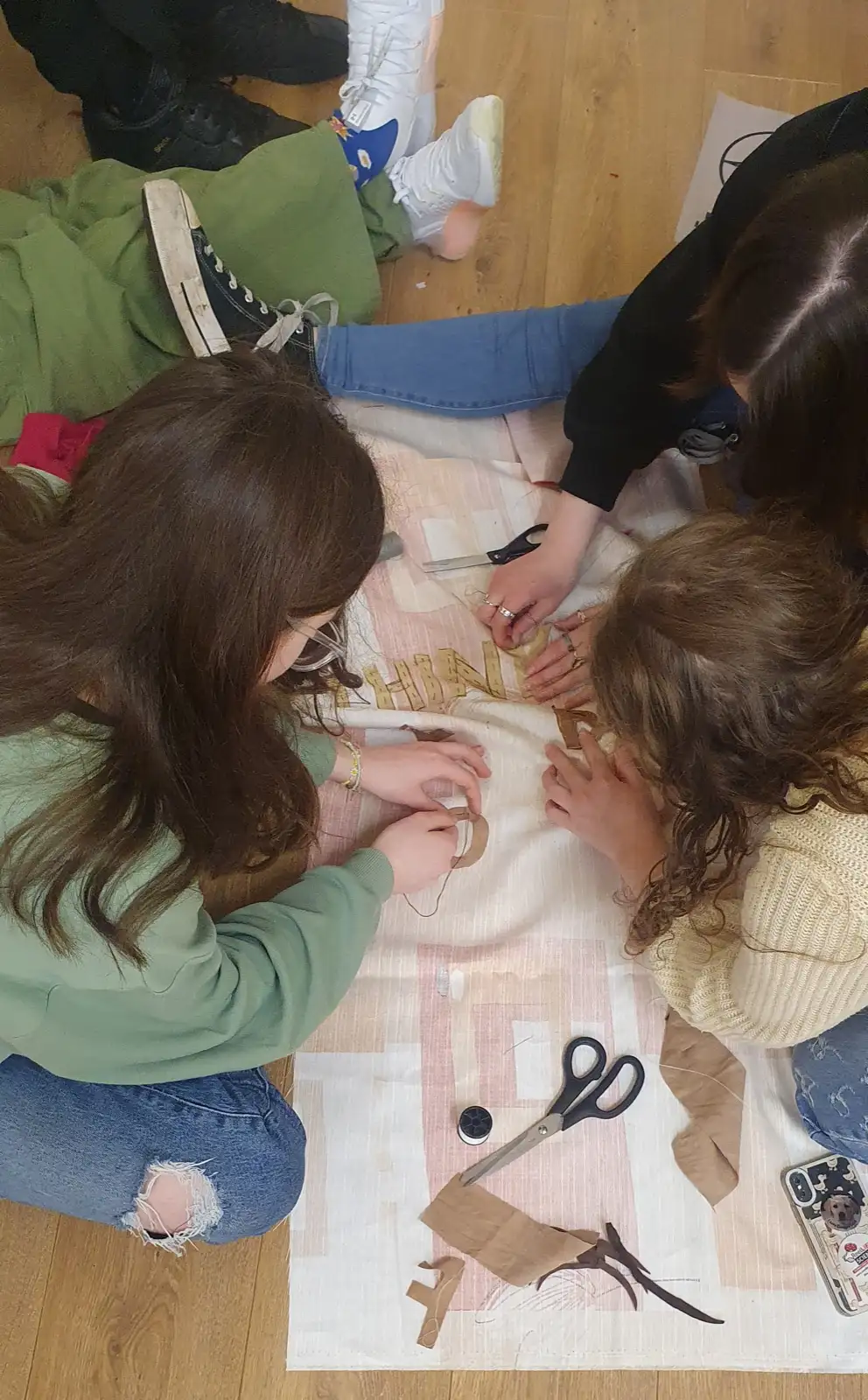 Three women collaborating on a fabric banner artwork